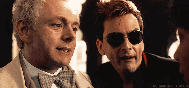 two men wearing sunglasses and bow ties are looking at something