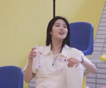 a woman is sitting in a chair with her legs crossed and holding a bottle of water .