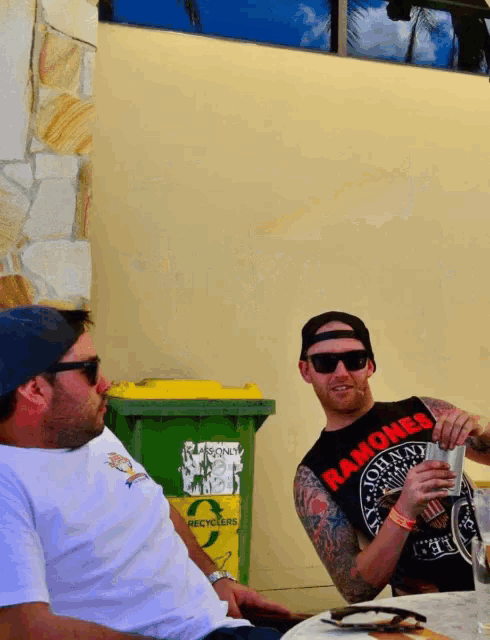 a man wearing a ramones shirt sits at a table