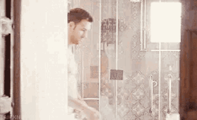 a man is standing in a bathroom with a shower curtain .