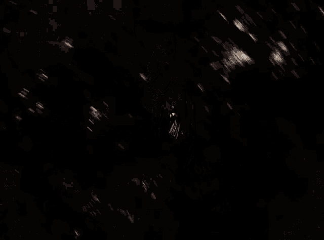 a man in a cape is flying through the air in the dark
