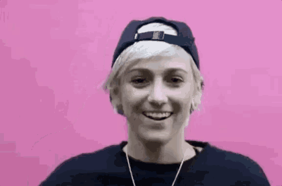 a woman wearing a baseball cap and a black shirt is smiling .