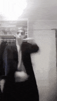 a man in a suit and sunglasses is dancing in a closet .