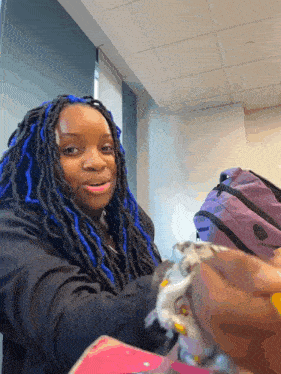 a woman with blue dreadlocks is smiling in front of a backpack