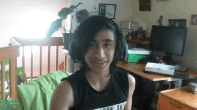 a young boy wearing headphones is smiling in front of a computer monitor .