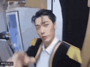 a man in a suit is making a funny face and pointing at the camera .