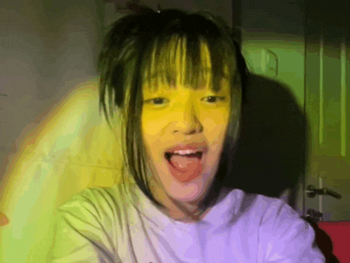 a girl with yellow paint on her face sticks out her tongue