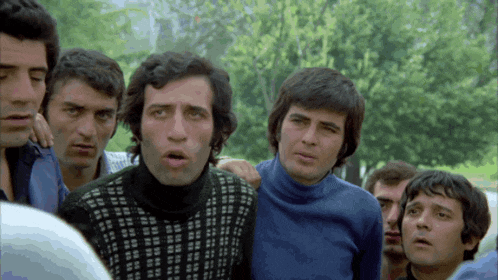 a group of men are standing together with one wearing a black and white sweater