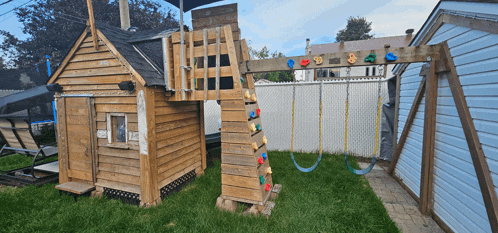 a backyard with a wooden playhouse and swings