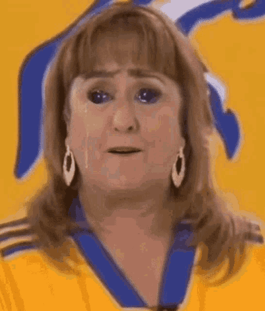 a woman is crying and wearing a yellow and blue shirt .