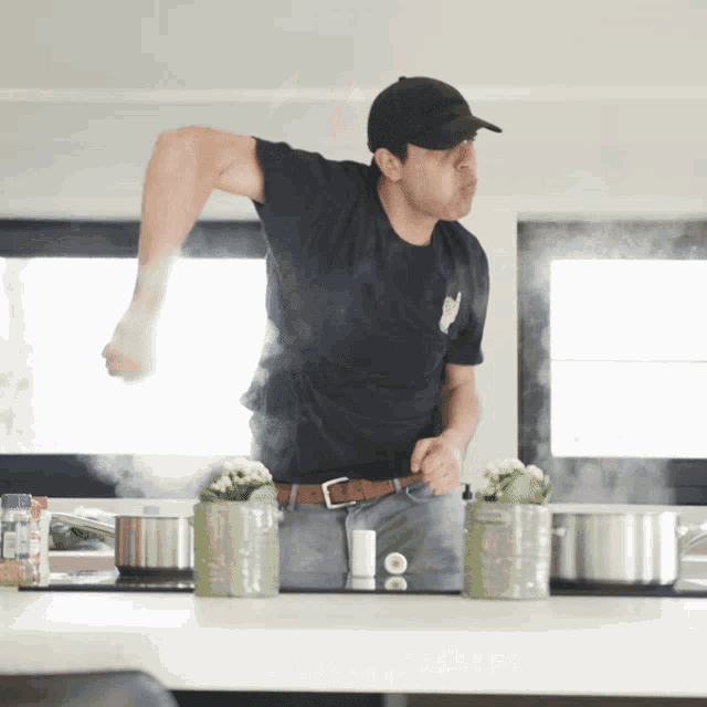 a man in a black shirt is standing in a kitchen with pots on the counter