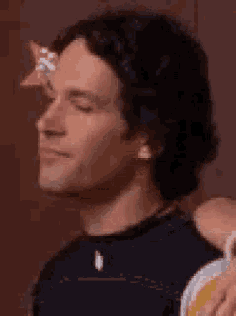 a close up of a man 's face with his eyes closed while holding a beer .