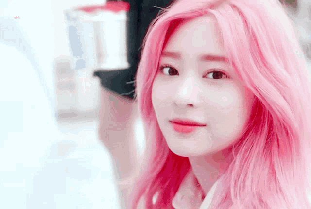 a woman with pink hair is looking at the camera with a blurry background
