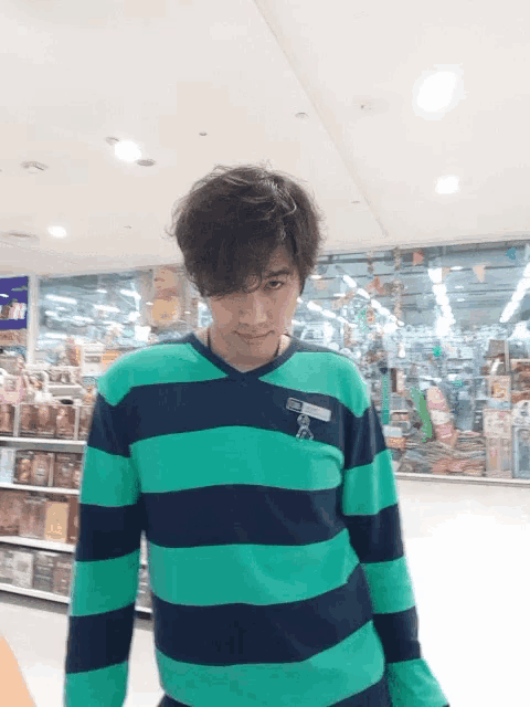 a man wearing a green and black striped shirt has a name tag that says ' t ' on it