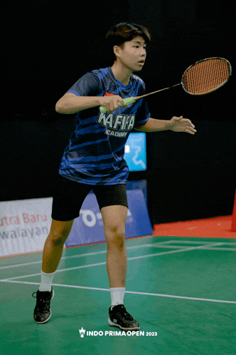 a person holding a badminton racket and wearing a shirt that says mafia