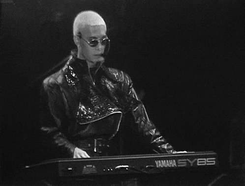 a man in a leather jacket is playing a yamaha sy85 keyboard