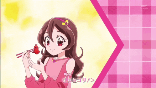 a girl in a pink shirt is holding a red object with chopsticks in her hand