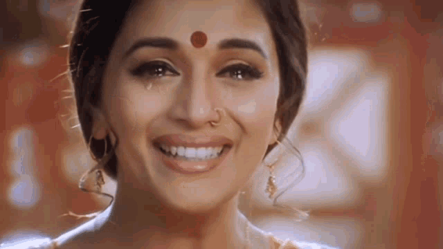 a woman with a red dot on her forehead is smiling and crying