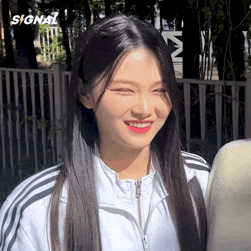 a girl wearing a white jacket with black stripes smiles for the camera