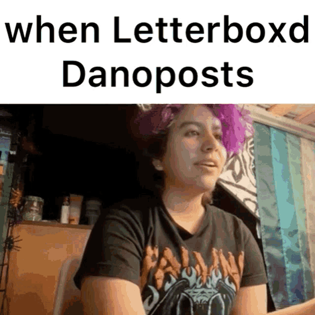 a woman with purple hair is sitting at a desk with the words " when letterboxd danoposts " on the bottom