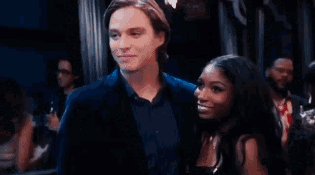 a man and a woman are standing next to each other in a crowd of people .