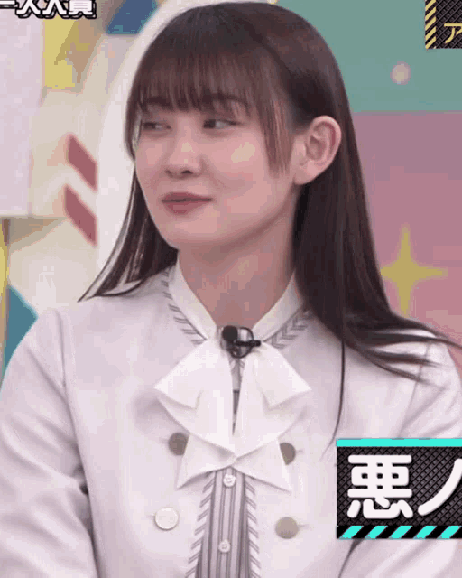 a girl wearing a white shirt with a bow tie and a microphone on her neck