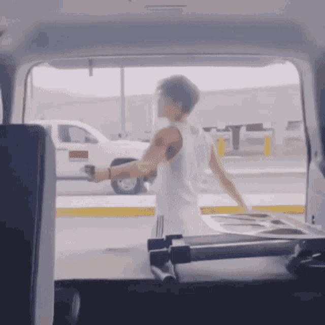 a man in a tank top is standing in the back of a van