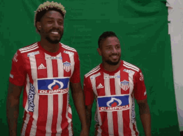 two soccer players wearing red and white striped jerseys with the word olimpica on them