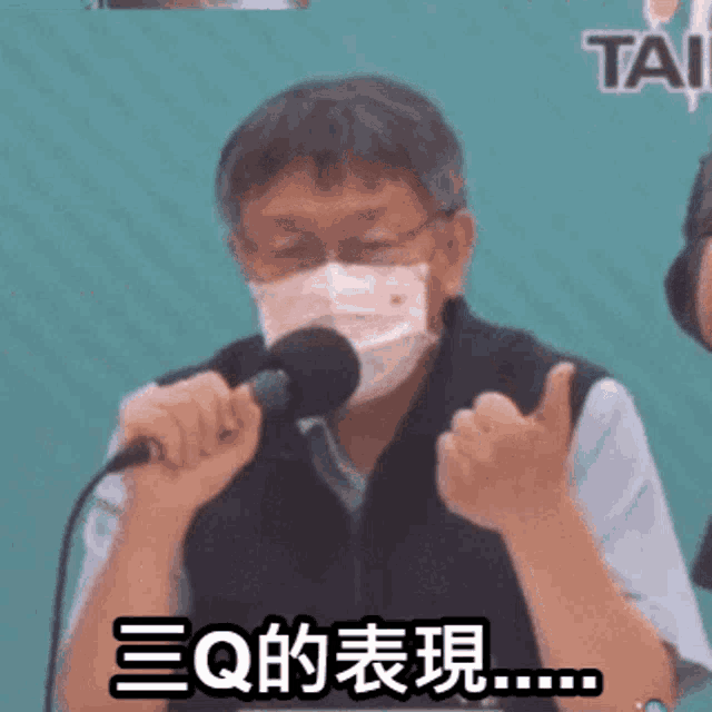 a man wearing a face mask is speaking into a microphone with chinese writing behind him
