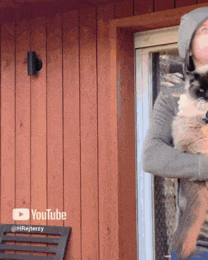 a man is holding a cat in front of a wooden wall with youtube written on it
