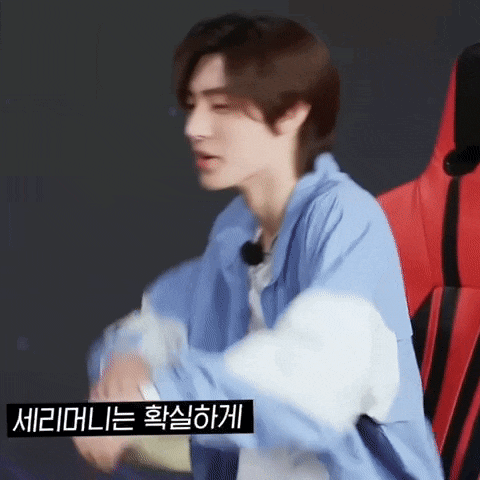 a man in a blue jacket is sitting in a red chair with korean writing on it .