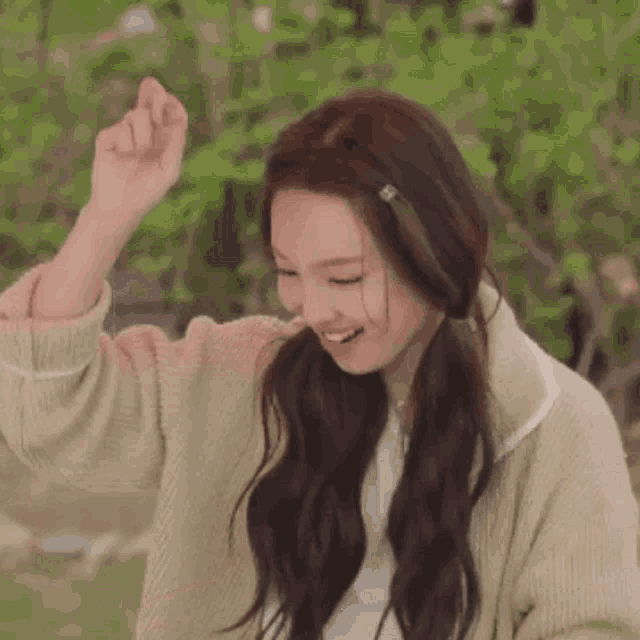 a woman in a sweater is raising her hands in the air .