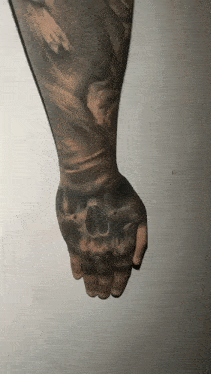 a man has a tattoo of a skull on his left hand