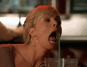 a woman is drinking through a green straw in a glass .