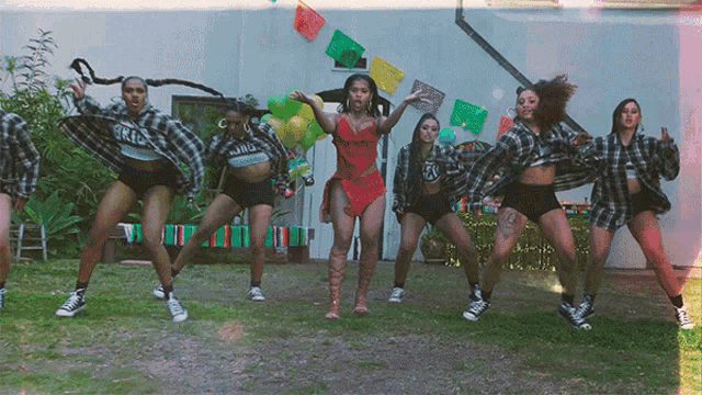a woman in a red dress is surrounded by dancers wearing shirts that say rio