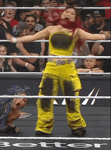 a woman in yellow pants is standing in a wrestling ring with the word better on the bottom