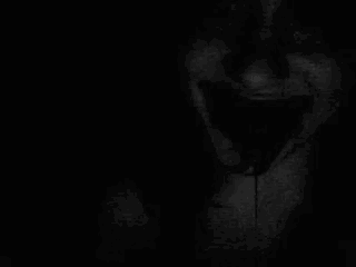 a close up of a person 's face in the dark with their mouth open and their eyes closed .