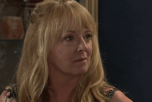 a close up of a woman 's face with blonde hair and bangs