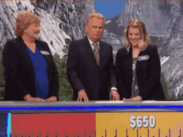 a man and two women standing in front of a $ 650 ruler