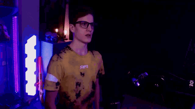 a young man wearing glasses and a yellow t-shirt with the letter a on the front
