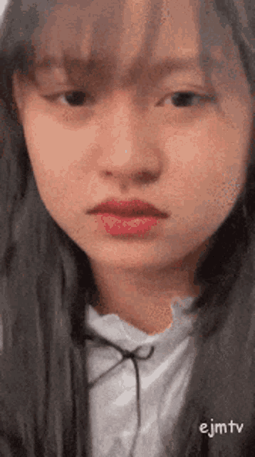 a close up of a woman 's face with a white shirt on and a hoodie on .