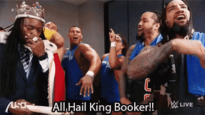 a group of wrestlers are standing in a locker room and one of them is wearing a crown and a tie .