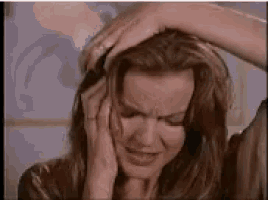 a woman is holding her head in pain while making a face .