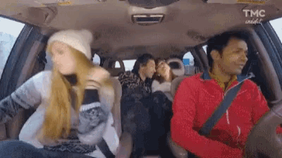 a man is driving a car with a group of people sitting in the back seat .