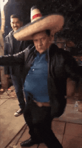 a man wearing a sombrero is dancing with another man in the background