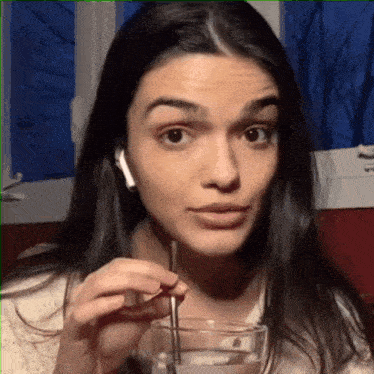 a woman is drinking through a straw and wearing ear buds