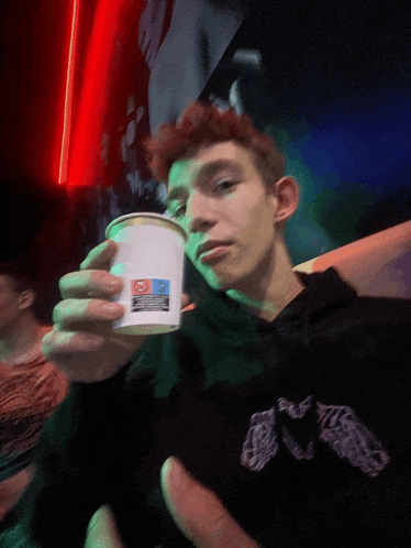 a man holding a cup with a sticker on it that says ' domino 's pizza '