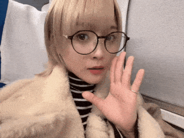 a woman wearing glasses is waving her hand