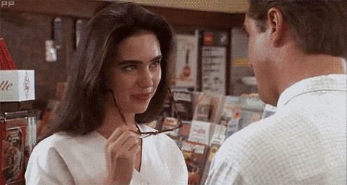 a man and woman are looking at each other and the woman is wearing glasses .