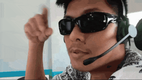 a man wearing sunglasses and a microphone giving a thumbs up sign